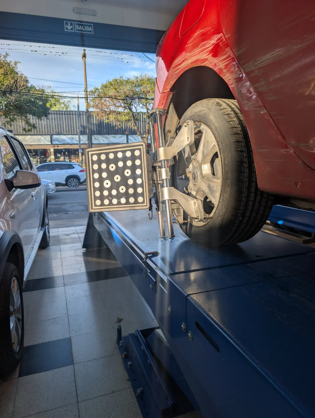 Auto sobre el elevador con el target de la alineadora 3D colocado en la rueda