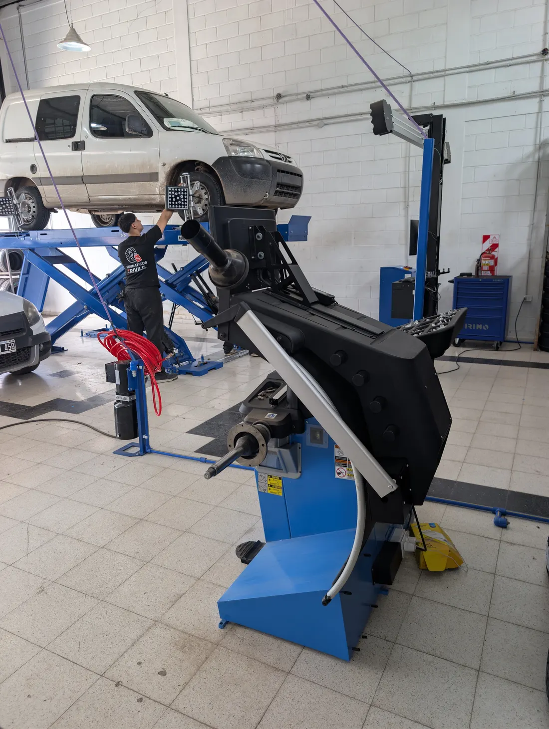 Utilitario sobre el elevador de alineación, con la balanceadora en primer plano