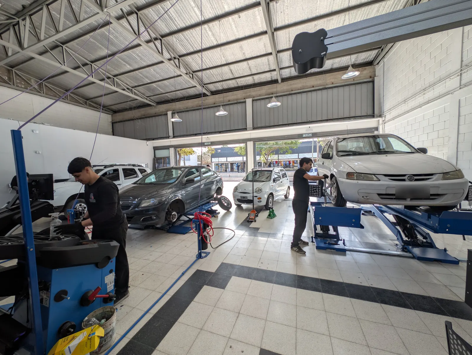 Interior del taller de Neumáticos Trivium en Argüello con cuatro autos en servicio